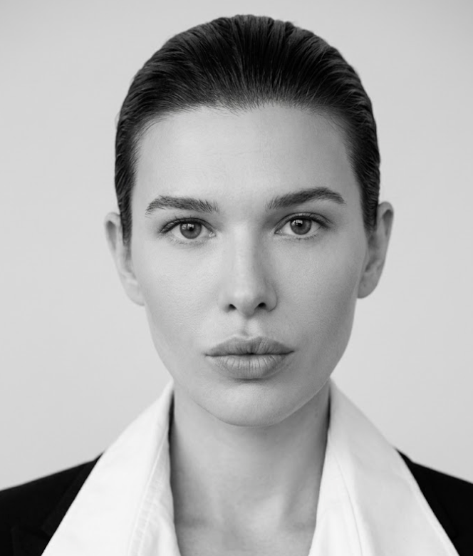 Black and white portrait of a person wearing a white shirt with a high collar.